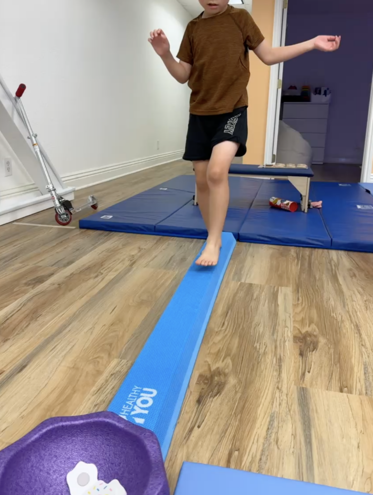 Child balancing on a blue foam beam.