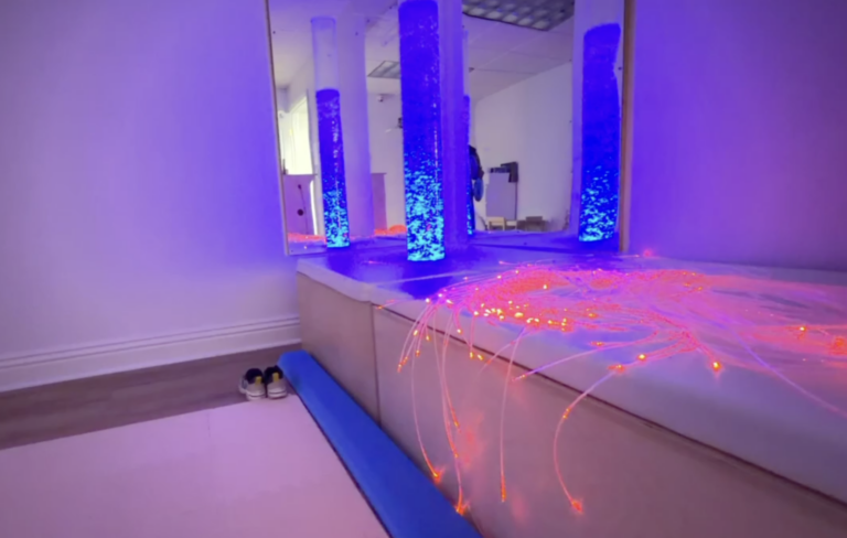Bubble columns and glowing pink fiber optic strands in the sensory room.