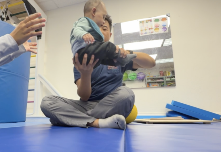 Therapist supporting a young child in a seated position.
