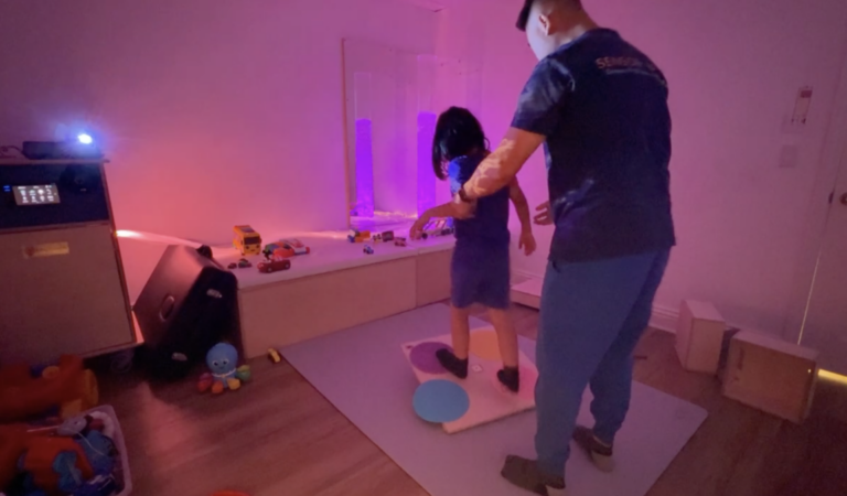 Therapist and child exploring projected lights and bubble columns.